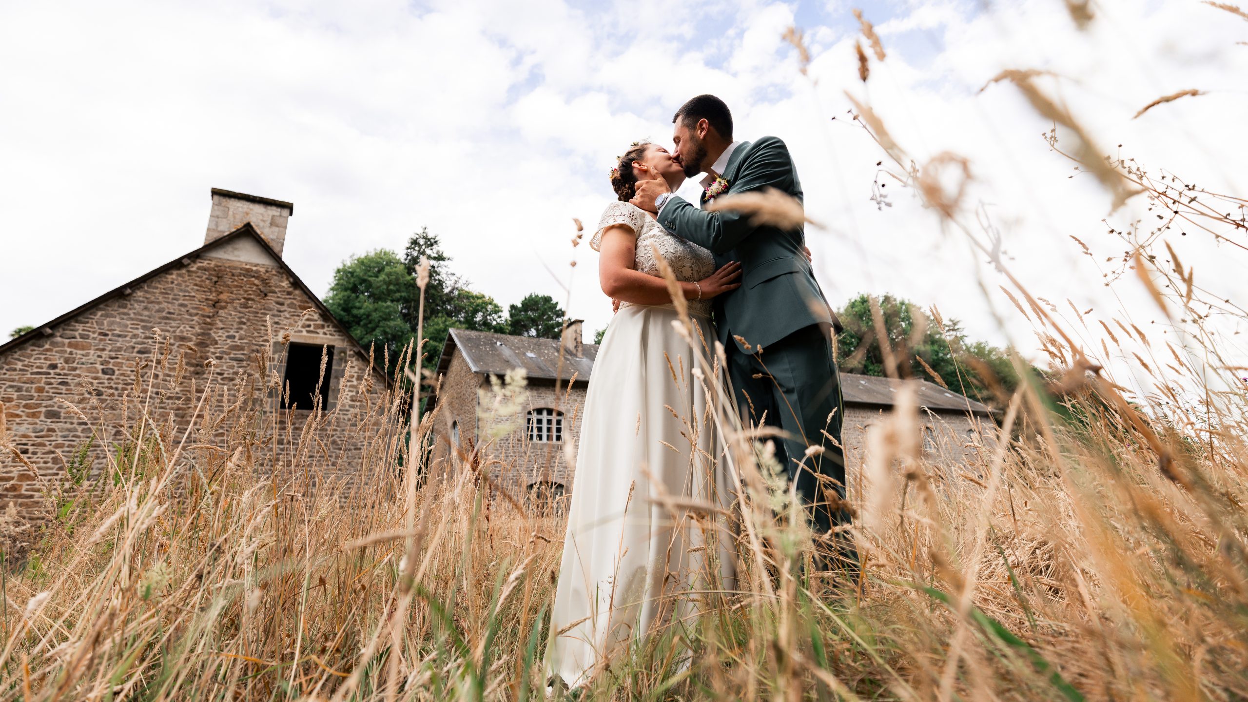 Mariés s'enlaçant tendrement dans un champ, photographie de mariage en Bretagne